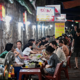 Một nhóm bạn trẻ đang ngồi quây quần bên bếp than đỏ lửa tại một quán nướng vỉa hè ở quận 8.